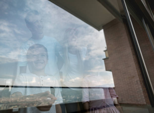 istock Happy family at home looking through the window 959398702