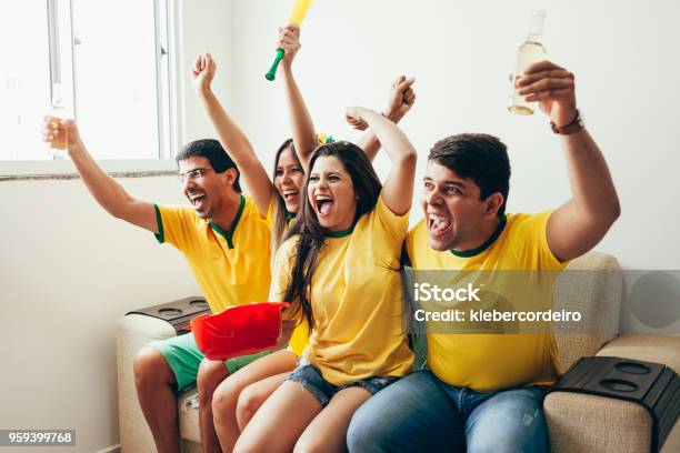 Group Of Friends Watching Soccer Game On Television Celebrating Goal And Screaming Stock Photo - Download Image Now