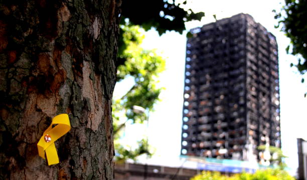 Grenfell Tower Yellow Ribbon Grenfell tower in the background with a Yellow Ribbon commemorating those lost pinned to a tree kensington and chelsea photos stock pictures, royalty-free photos & images