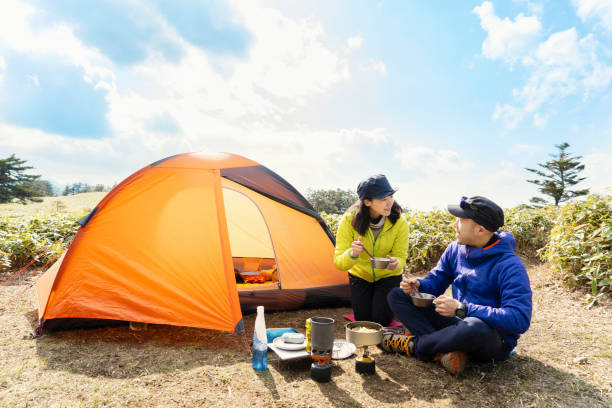мужчины и женщины, наслаждающиеся приготовлением пищи на открытом воздухе в кемпинге на природе - camping hiking tent couple стоковые фото и изобр�ажения
