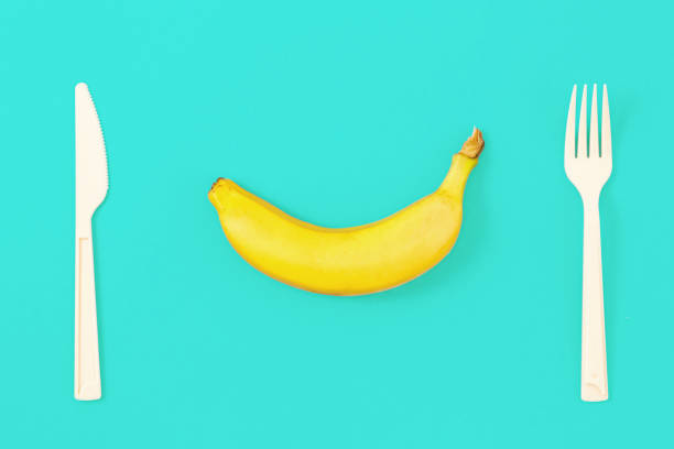 istock Ripe banana on blue background with fork and knife. Top view, flat lay 959424230