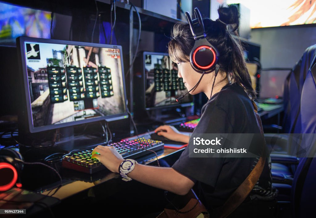 young girl playing computer games in internet cafe Gamer Stock Photo