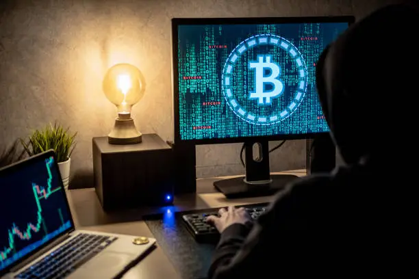 Photo of Hacker man using laptop and computer with  green binary graphic and cryptocurrency candlestick graph price on monitor screen
