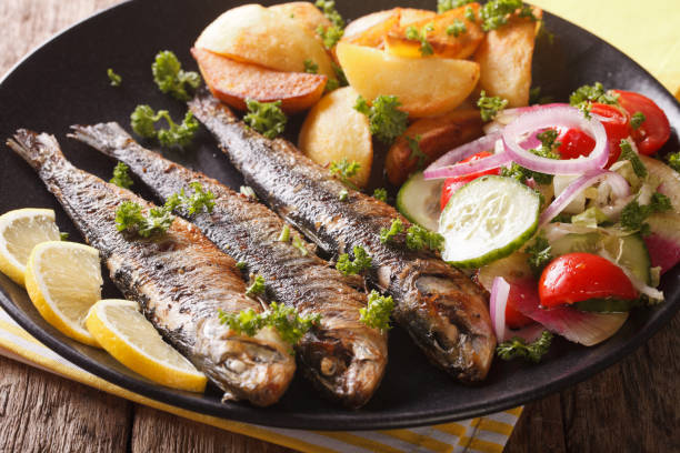 gebratene sardinen mit kartoffeln und salat aus frischem gemüse nahaufnahme. horizontale - close up green plate salad stock-fotos und bilder