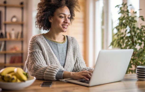 istock Beautiful black woman blogging on her computer while relaxing at home. 959447560