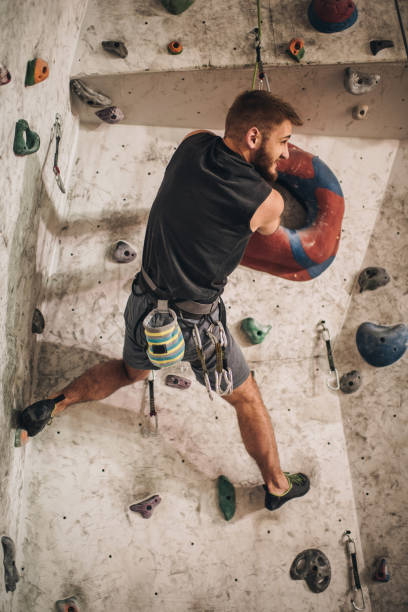 istock Back view of athletic man climbing on the wall in a gym. 959448190