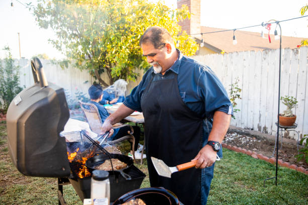 Senior Mexican Man Grilling Steaks at BBQ Senior mexican man grilling steaks at a BBQ fat mexican man pictures stock pictures, royalty-free photos & images