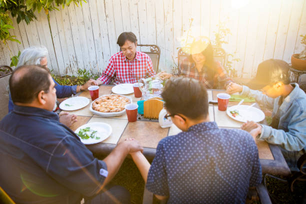 Diverse Group of Friends and Family Praying before Dinner