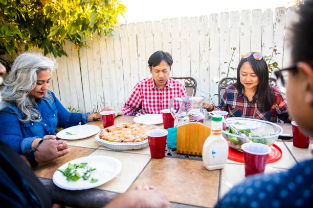 istock Diverse Group of Friends and Family Praying before Dinner 959451464