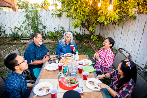 Diverse group of friends having dinner outdoors at a backyard bbq