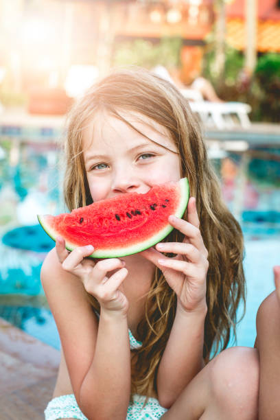 летние каникулы - дети едят арбуз у бассейна в таиланде - watermelon fruit healthy eating snack стоковые фото и изображения