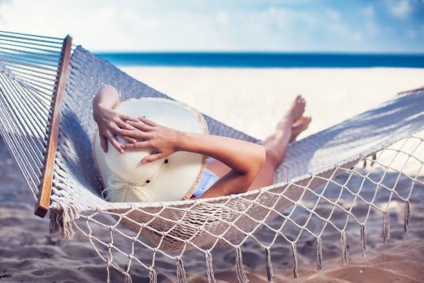 istock Woman relaxing on hammock with white hat sunbathing on vacation 959458224