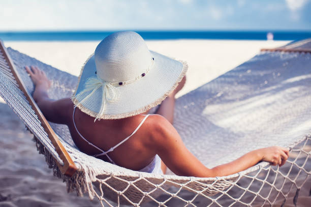 istock Woman relaxing on hammock with white hat sunbathing on vacation 959458226