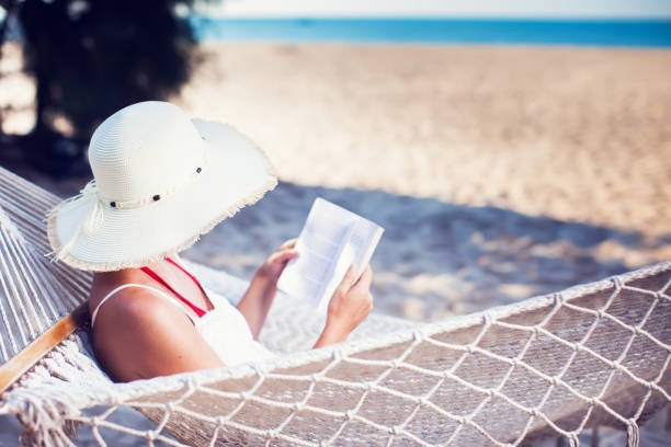 istock Young lady reading a book in hammock on tropical sandy beach 959458314