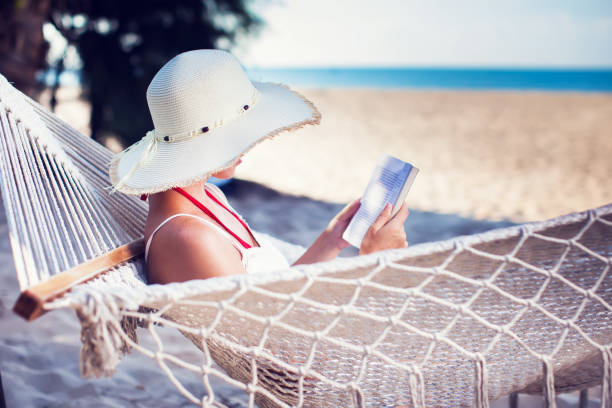 istock Young lady reading a book in hammock on tropical sandy beach 959458320