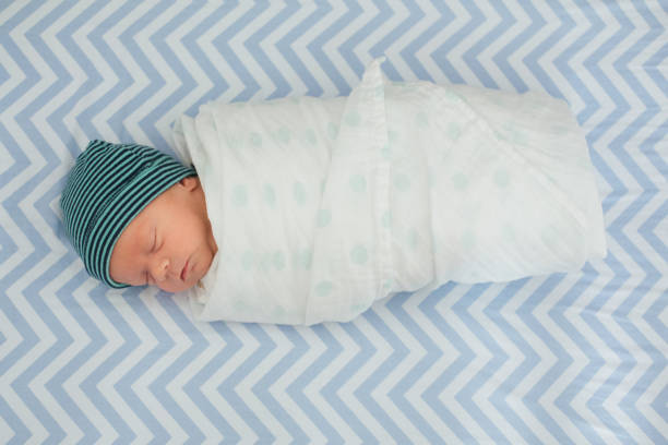 One month old baby wrapped in a swaddle blanket stock photo