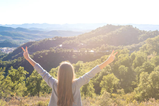 istock Beautiful women showing peace sign while enjoying mountains landscape 959469330