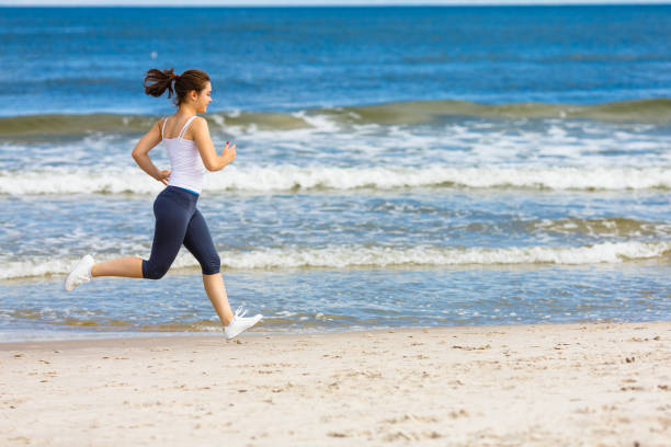 istock Young woman running on beach 959469436