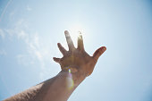 Man's hand reaching out for sun light