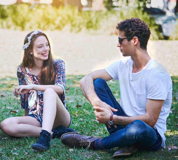 istock Handsome young couple relax, sitting on grass lawn 959473196