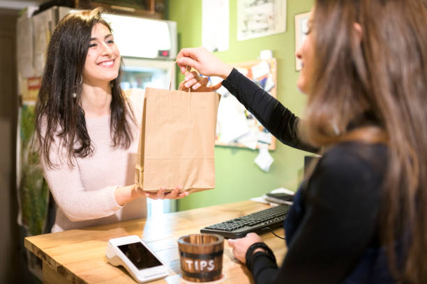 Saleswoman handing paper bag to customer stock photo