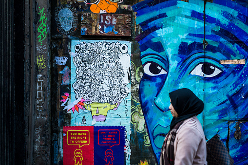 London, UK - 25 January, 2018: profile view of a Muslim woman, wearing the traditional hijab, on Brick Lane in London, UK. Beyond here the walls are covered in graffiti. Lots of room for copy space.