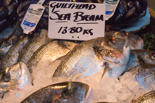 Sea Bream for sale with designs and logos visible in the background in Borough Market, London