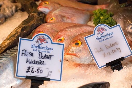 Mackerel and sea bream for sale with designs and logos visible in the background in Borough Market, London