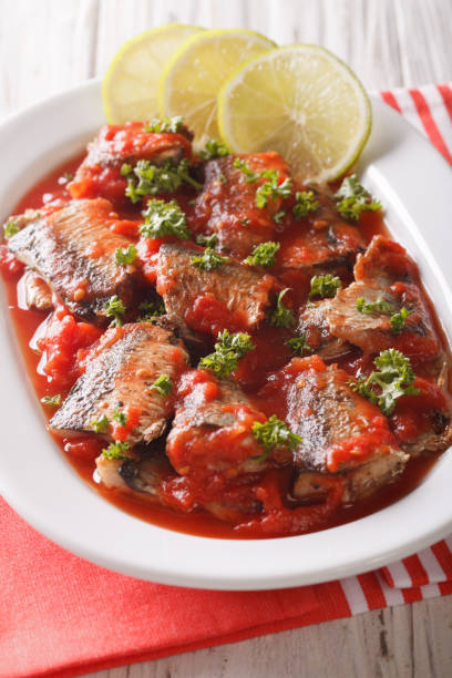 istock Braised sardines in tomato sauce with lime and parsley close-up. Vertical 959492676