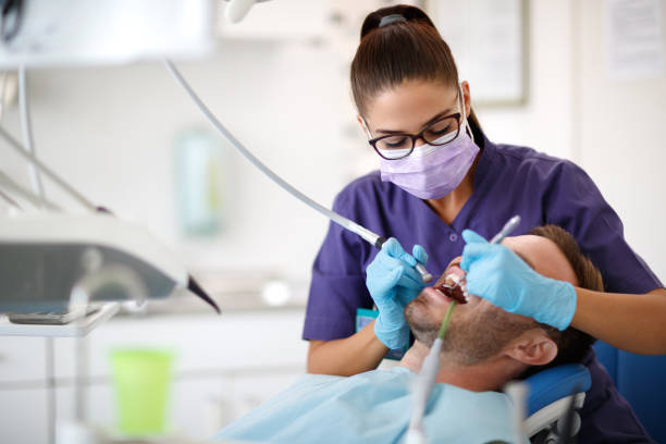 istock Young female dentist drilling tooth to patient 959494436