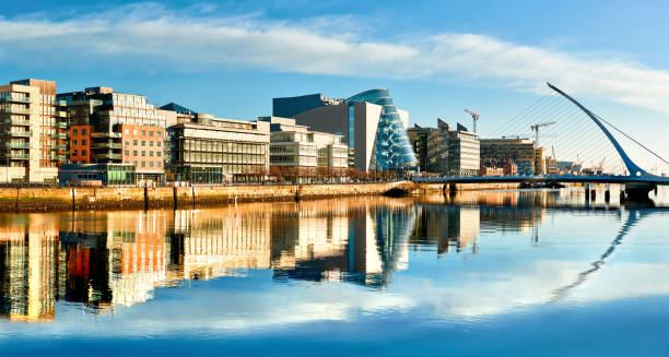 edifici e uffici moderni sul fiume liffey a dublino in una luminosa giornata di sole - ponte di strumento musicale foto e immagini stock