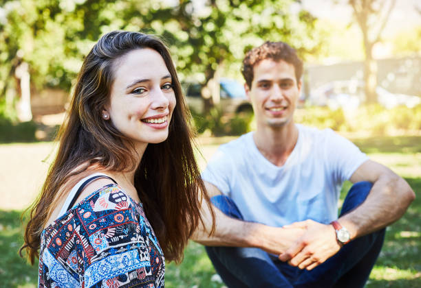 istock Happy and romantic young couple sitting on grassy lawn 959498832