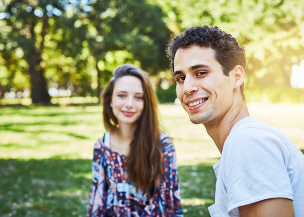 istock Good-looking, romantic young couple sitting in leafy park 959499190