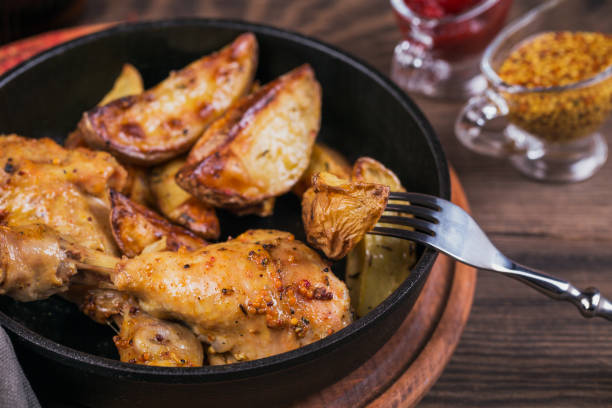 istock Fried chicken legs with fried potatoes in pan 959503248