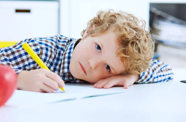istock Tired little boy sitting at the table, with hishead on his arm 959508866