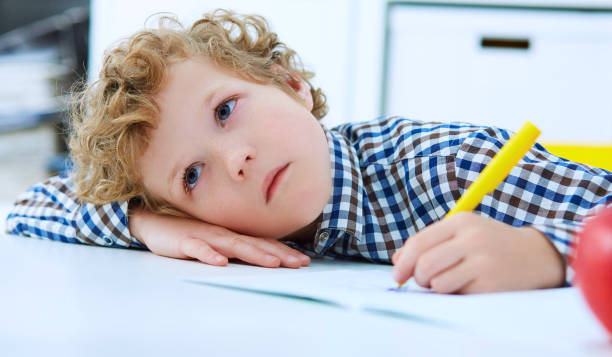 istock Tired little boy sitting at the table, with hishead on his arm 959508908