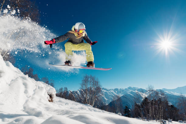 mädchen springt mit snowboard - skiurlaub stock-fotos und bilder