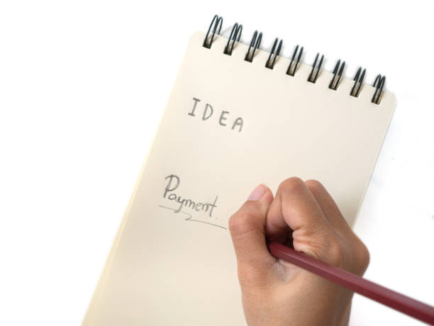 istock Asian female hand with pencil writing on yellow notebook 959512404