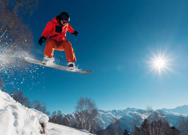 snowboarder is jumping with snowboard from snowhill stock photo