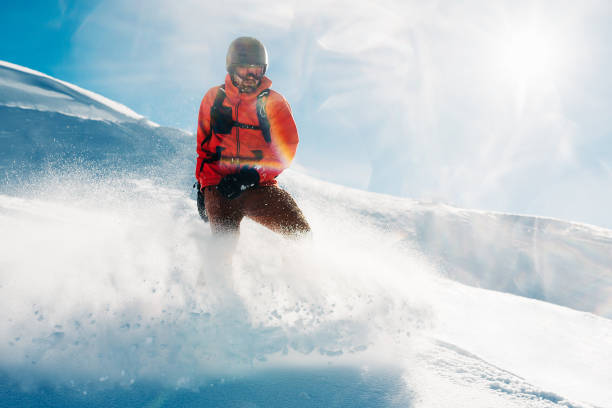 snowboardzista stoi w czerwonym garniturze na wzgórzu z proszkiem śnieżnym i patrzy w dal - skiing winter sport powder snow athlete zdjęcia i obrazy z banku zdjęć