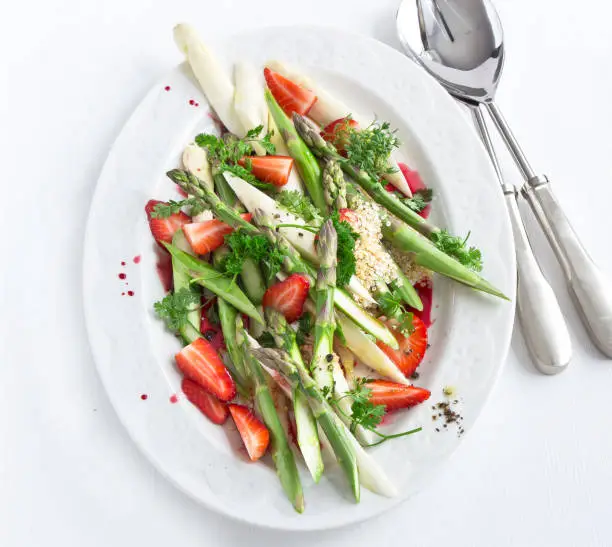 asparagus salad from white and green asparagus with strawberries on white plate