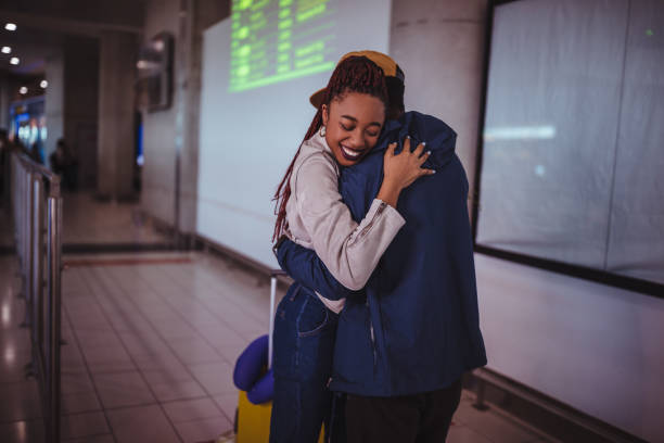 Young loving couple embracing at airport after travel Happy couple meeting at airport and hugging after flight arrival airport hug stock pictures, royalty-free photos & images