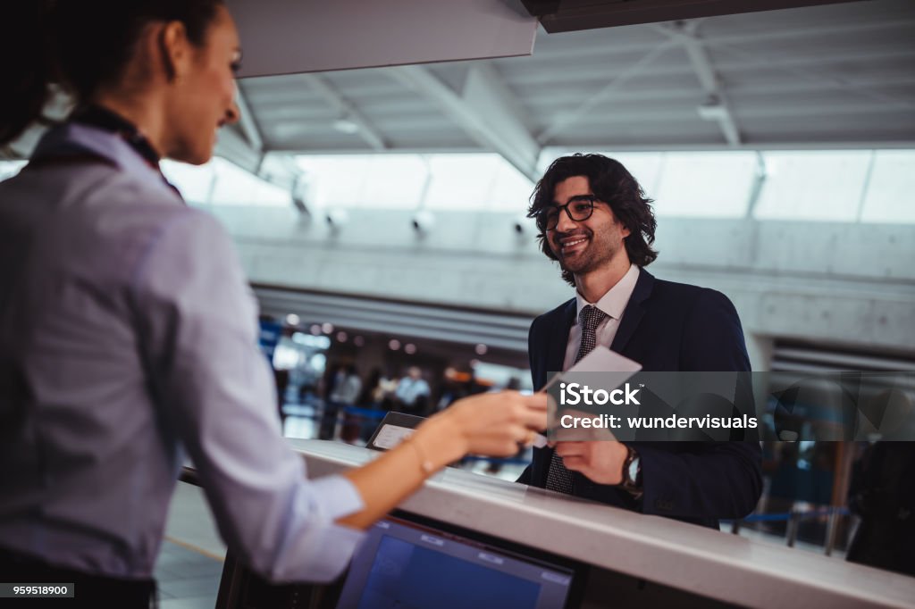 Businessman doing check-in and getting boarding pass at airport Airline attendant giving boarding pass and passport and doing check-in for businessman at international airport Airport Stock Photo
