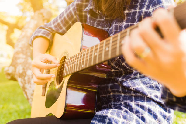 istock Female fingers playing guitar outdoor 959522868