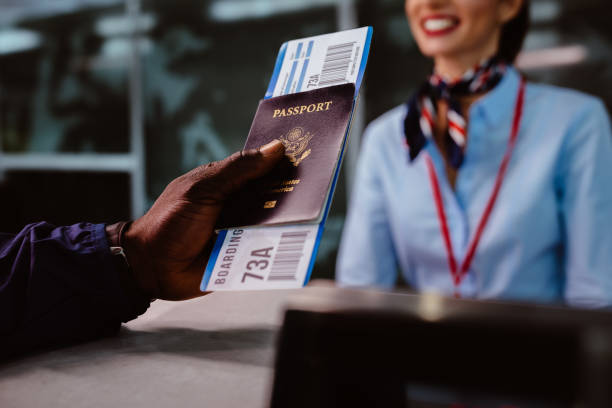 l’homme détenteurs d’un passeport et d’embarquement passent au comptoir d’enregistrement d’avions - zone denregistrement photos et images de collection