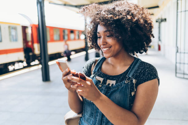 istock Smiling woman using smart phone on station 959527288