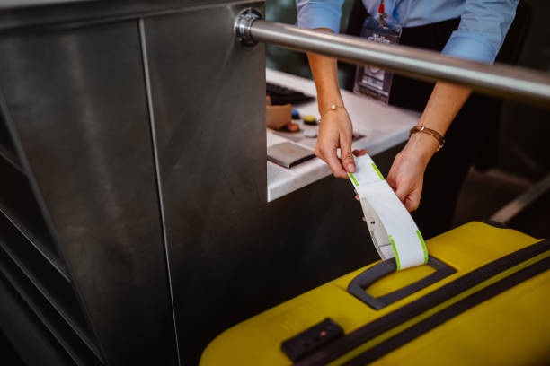 empleado de mostrador de facturación del aeropuerto colocar etiqueta de equipaje - área de embarque fotografías e imágenes de stock