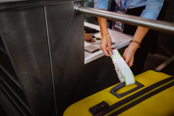 employé de l’aéroport au comptoir d’enregistrement attachant tag sur les bagages - personnel aérien au sol photos et images de collection