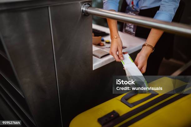 Airport Checkin Counter Employee Attaching Tag On Luggage - Fotografias de stock e mais imagens de Aeroporto