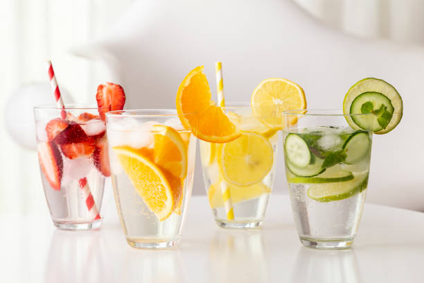Fresh infused waters Glasses of infused water with fresh strawberries, lime, cucumber and mint leaves, lemon and orange. Focus on the orange slice on the glass infused water stock pictures, royalty-free photos & images